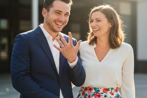 結婚指輪を見せ合いながら幸せそうに微笑み合うスーツ姿の男性とオフィスカジュアルの女性