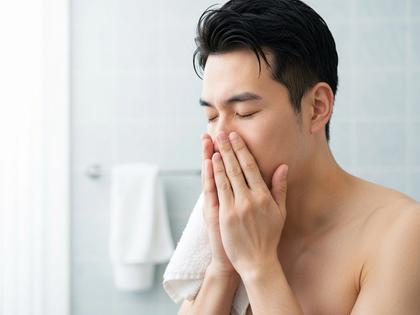 洗顔後にタオルで顔を押さえる男性、清潔感のある雰囲気