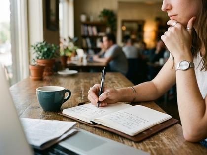 ノートに書き出して考える女性の手元、ペンとリスト