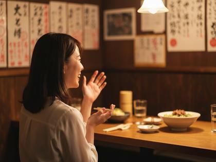 居酒屋で楽しそうに会話する20代女性の後ろ姿