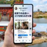 佐賀の景色を背景に、SAGA CONNECTアプリ画面のスマートフォン。