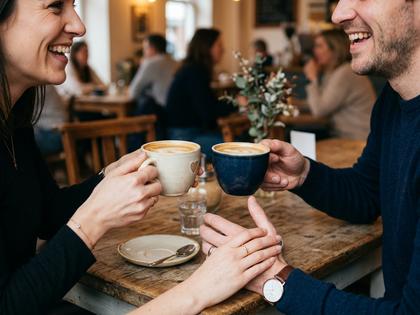 カフェで談笑する男女の手元とコーヒーカップ