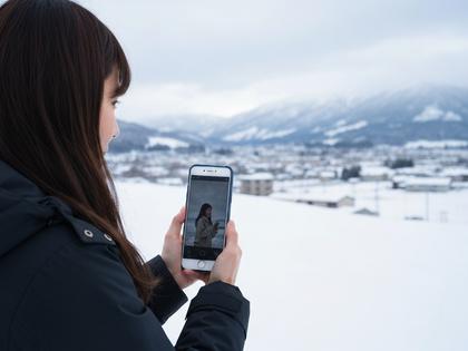 岩手の雪景色とスマートフォンを手にする女性のイメージ