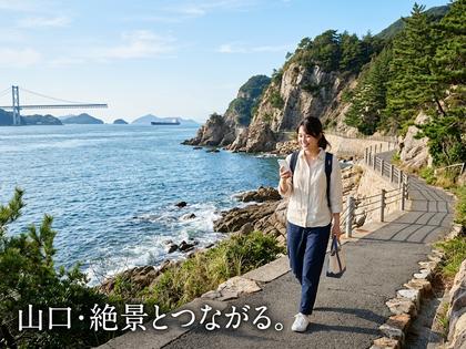 山口県の海沿いを歩く20代女性がスマホを見ているイメージ