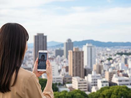 大分の街並みとスマートフォンを持つ女性のイメージ