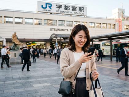 宇都宮駅前でスマホを見ながら微笑む20代女性