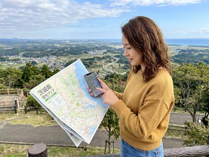 茨城県の地図とスマホを照らし合わせて検討する女性