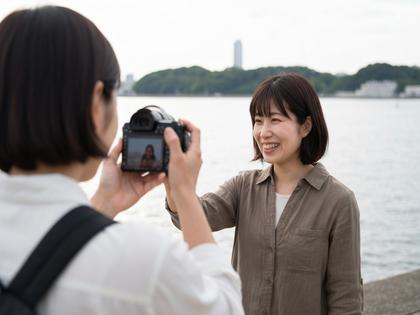 中之島の水辺で笑顔の女性が友達に撮影してもらっているシーン