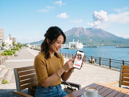 桜島を背景にスマホでマッチングアプリを使う鹿児島の女性
