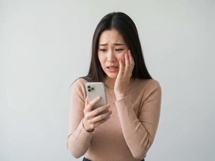 スマホを見て安堵の表情を浮かべる20代女性のイメージ