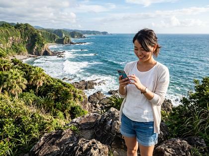 宮崎の海岸沿いでスマートフォンを操作する20代後半の女性