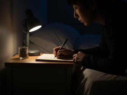 ベッドサイドでノートに書き込む夜の様子