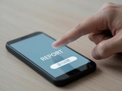 スマホで通報ボタンを押す手元のクローズアップ
