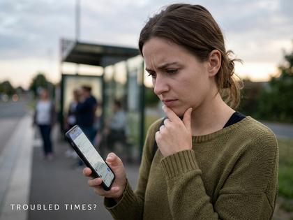 困った表情でスマホを見る女性のイメージ