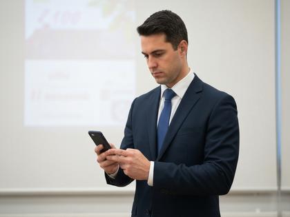 スーツ姿の公務員男性がスマホを見ているイメージ