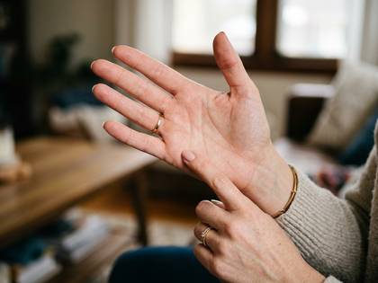 指輪をつけた手が、もう一方の手のひらをそっと触っている。
