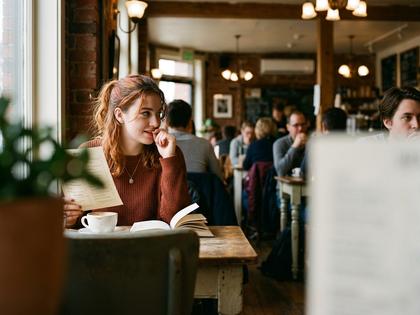 カフェで気になる人を見つめる若い女性のイラスト