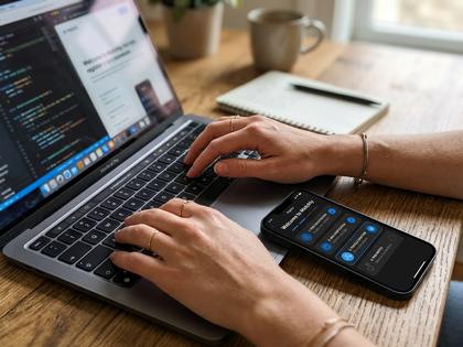 ノートパソコンとスマートフォンで会員登録画面を確認している女性の手元