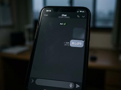 夜の部屋でスマートフォンを置いてため息をついている女性、ベッドサイド、800×600