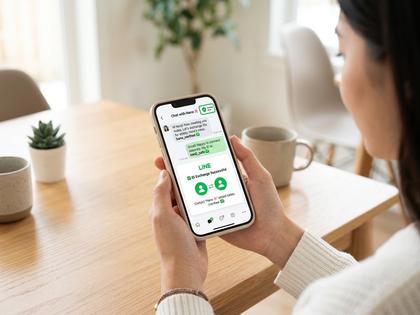 スマートフォンでワクワクメールのメッセージ画面を見ながら考えている20代女性、明るい室内、800×600
