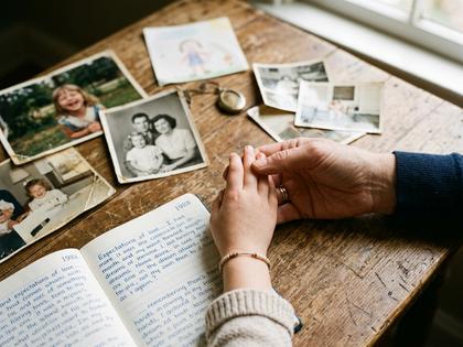 子ども時代の写真アルバムをめくる女性の手元、温かみのある室内、800px×600px