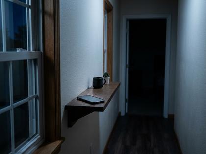 寝室のドアの外、廊下の棚に置かれたスマートフォン、夜の静かな室内、800px×600px