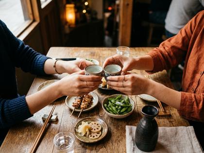 テーブルに並んだ日本酒のグラスとおつまみ、談笑する女性たちの手元